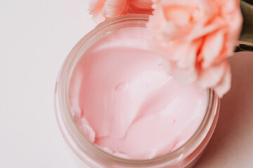 Open jar with pink cream and flowers. High quality photo