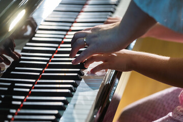 Teacher guiding child playing piano keys
