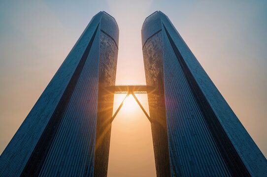 Golden sunrise beams break between modern towers creating serene geometry in glowing urban morning atmosphere