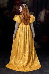 A red-haired woman wearing a historically styled gold gown with puffy sleeves