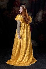 A red-haired woman wearing a historically styled gold gown with puffy sleeves