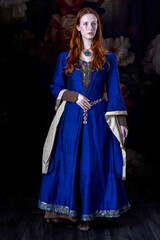 Medieval or high fantasy woman wearing a blue silk dress with hanging gold sleeves