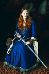 Medieval woman wearing a blue silk dress and holding a sword