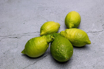 Fresh green limes scattered on a gray stone surface