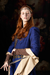 Medieval or high fantasy woman wearing a blue silk dress and holding a dagger