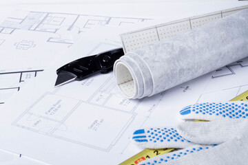 Laying flooring. Linoleum, a knife and a house plan on the builder's table. Taking measurements for laying the floor..