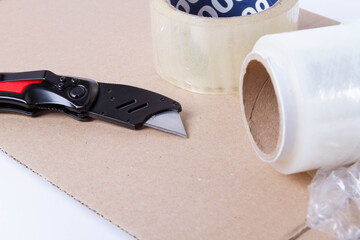 Packing the goods in a cardboard box and stretch film. Tools for packing parcels at the post office..