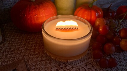 Candle with a unique blade decoration surrounded by seasonal decorations in a cozy autumn setting