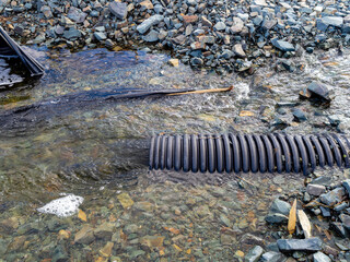 Flood damage on a small river caused by heavy rain and an undersized culvert.