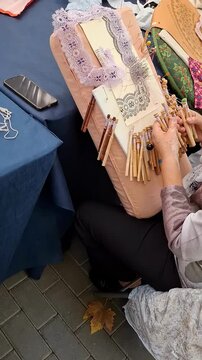 Discover the skill of crafting Valencian bobbin lace as expert hands manipulate bobbins to create intricate patterns. This traditional art form captivates with its beauty and detail.