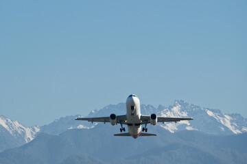 Airplane Climbing into Winter Sky Above Snowy Mountain Landscape. Powerful Takeoff of Commercial...