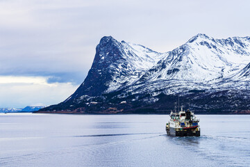 Berge und Fischerboot im Winter nahe Harstad in Norwegen