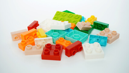 a pile of small plastic blocks or plastic blocks of various shapes, sizes, and colors that can be connected to each other and assembled into various shapes, isolated on a white background © PinkyEn