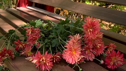 Beautiful arrangement of pink flowers and greenery resting on a wooden bench in a tranquil park setting