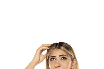 Fototapeta premium Half portrait Close-up of blonde woman scratching her head and looking up with curious expression, empty white background with copy space above head, studio shot