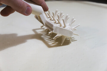 Close-up of a professional dough docker perforating pizza dough to prevent air bubbles during baking. Stainless-steel kitchen tool used in pizzerias and commercial kitchens. Close up. 