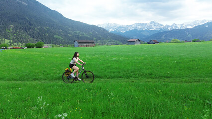 Happy female cyclist in green mountain meadow