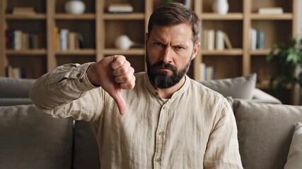 Intense bearded man with a serious gaze looking directly at you from his couch, creating a powerful impression of determination and unwavering focus