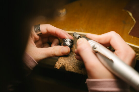 Jewelry ring hands polishing with rotary tool in workshop for craftsmanship and artisan creation metalworking and detailed finishing handmade accessory