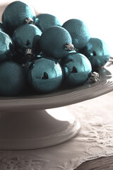 Shiny turquoise christmas baubles on white ceramic stand for festive decor concept of winter holidays and home styling