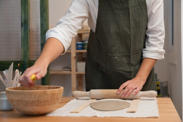 Artist rolling clay with pin in pottery workshop