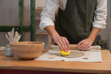 Potter's hands working clay slab in workshop
