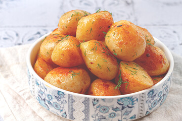 Baked new potatoes, with butter and dill, on a white plate, at home, no people,