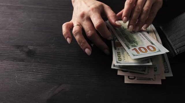 Girl Removing Hundred Dollar Bills From A Black Leather Wallet In The Usa
