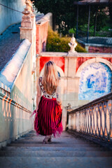 Woman walking down historic staircase at Estoi Palace during golden hour