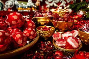 Luxurious Christmas decorations in rich red and gold. Shiny balls, festive ornaments, a pine branch create a warm, opulent holiday scene perfect for seasonal marketing and luxury branding.