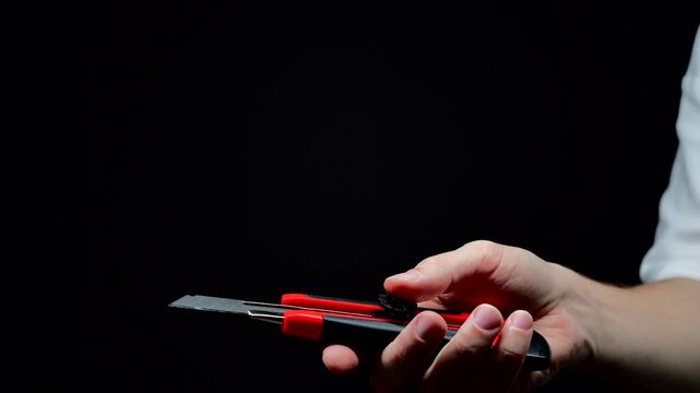 A sharp utility knife in a man's hand.
A man uses a utility knife for office work.
A paper cutter