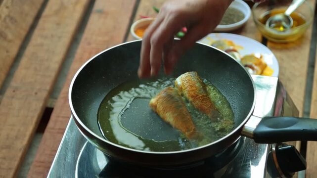 Fish pieces are frying in pan in mustard oil.