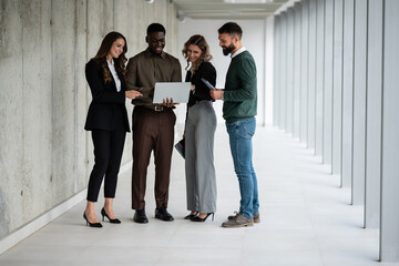 Business professionals collaborating in modern office hallway discussing project