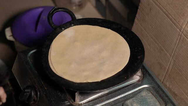 close up of a woman making roti on tawa.