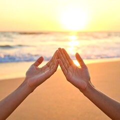 Hands framing the sun on a serene beach at sunset.