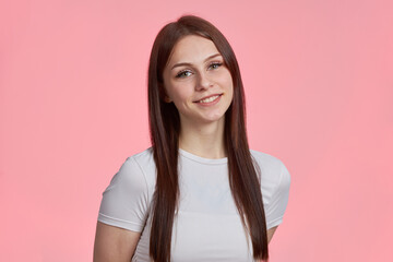 Portrait of a young beautiful student girl in a white T-shirt isolated on a pink background
