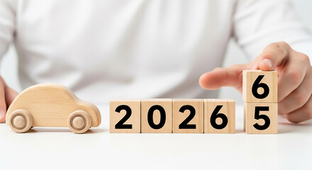 Wooden car beside cubes displaying year with hand adjusting last cube for future planning concept 