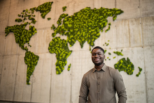Young man smiling by green moss world map