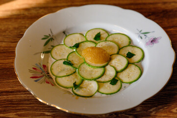 Zucchini carpaccio with pollock caviar and mint leaves on a vintage plate.