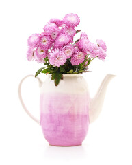 Pink chrysanthemum bouquet in a ceramic teapot vase on white background.