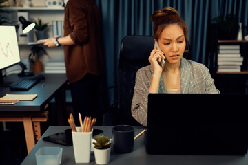 Businesswoman calling with customers to make new project job at modern office while coworker checking paperwork folder of business plan to database report meeting at over late night time. Infobahn.