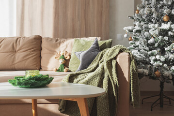 Cozy Living Room with Crocheted Reindeer Toy on Sofa and Christmas Holiday Candle Decor on Table