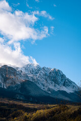 Snow-capped mountains towering over valley, bright blue sky with white clouds, dramatic Gran Sasso landscape, Abruzzo, Italy