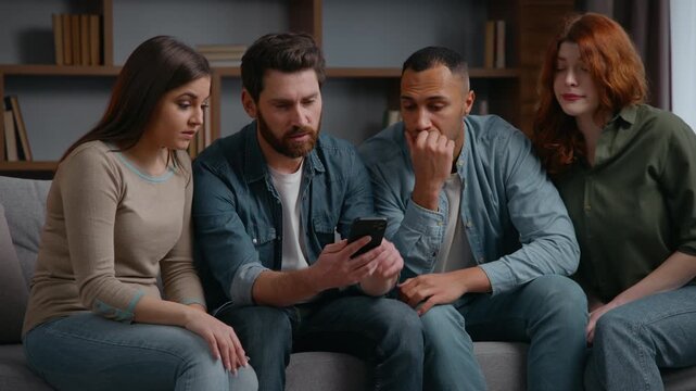 Four multiracial friends at home party looking in mobile phone lost bet casino failure confused sad diversity multiethnic people men women watching sport game streaming on smartphone bad result shock