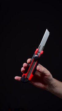 A sharp utility knife in a man's hand.
A man uses a utility knife for office work.
A paper cutter