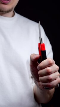 A sharp utility knife in a man's hand.
A man uses a utility knife for office work.
A paper cutter