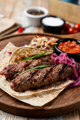 Delicious grilled kebabs rest on a wooden platter accompanied by vibrant sides like tangy slaw and rich sauces, igniting appetites at a sunny gathering