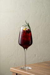 This vibrant drink showcases a blend of rich colors and fresh garnishes. Served in an elegant glass, it is beautifully complemented by slices of citrus and a sprig of rosemary, ideal for any occasion