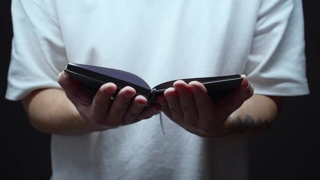 A man reads the Bible and turns to God with a request.
Communication with God.
A religious man with an open Bible in his hands against a black background.
Religion, prayer, God. Christian, Bible, read