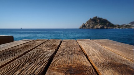 A rustic wooden table sits near the shore overlooking the sparkling blue sea. In the background a rocky island rises against the clear sky creating a serene atmosphere.